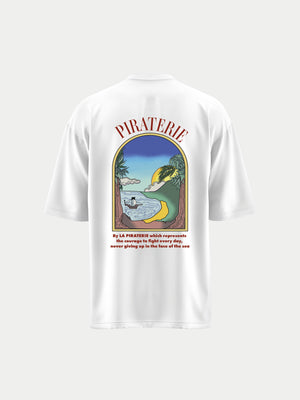 Dos uni du même t-shirt blanc, imprimé en grand du même paysage tropical dans une arche colorée avec le mot « Piraterie » en haut et la citation « Live Free. Sail Wild. » en bas, accentuant le caractère voyageur.
